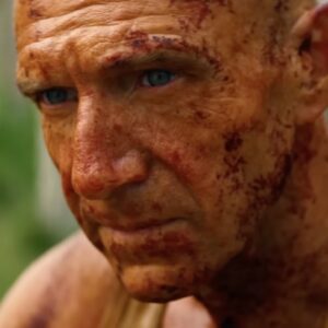 aging bald man covered in grime looking contemplative.