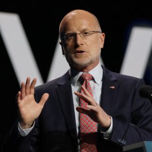 FCC Chairman Brendan Carr speaks while standing on a stage in front of a podium.