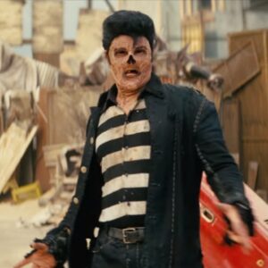 ghoul with missing nose in ruins of Vegas dressed as an Elvis impersonator