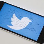 A Twitter logo on a phone with a shattered screen.