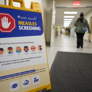 A person walks past a measles screening sign near an entrance at Victoria Hospital in London, Ontario, on July 9, 2025.