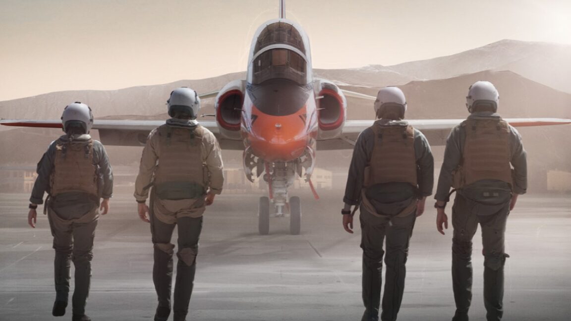 backs of four fighter pilots walking toward a fighter jet