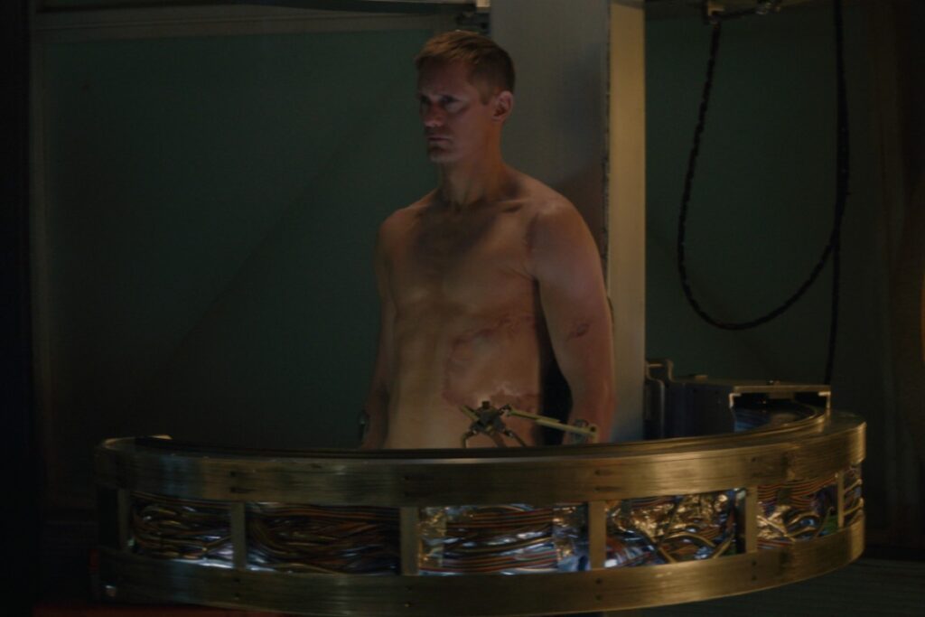 nude murderbot getting stitched up in a bioprinting apparatus.