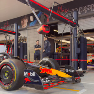 A Red Bull F car in the pit lane, with another Red Bull F1 car in the background still in its garage bay.