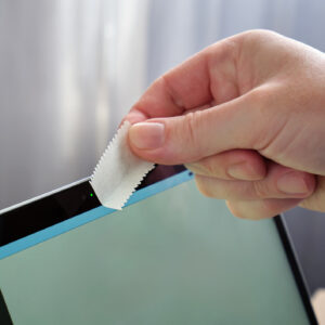 male hand covering webcam with tape